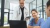 zwei Krankenschwestern und ein Arzt schauen lächelnd auf einen Laptop